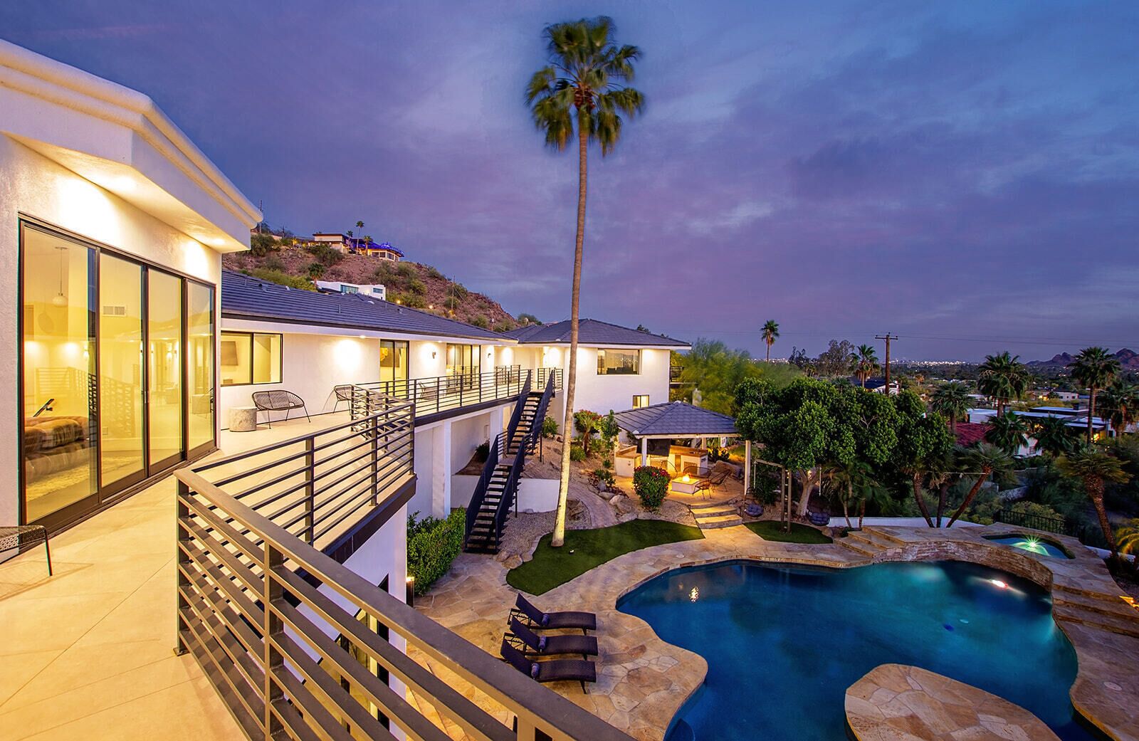A modern house with a pool, a staircase, and a patio area.