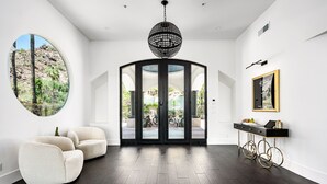 Un intérieur moderne avec une fenêtre circulaire, un lustre noir et une vue sur un patio extérieur.