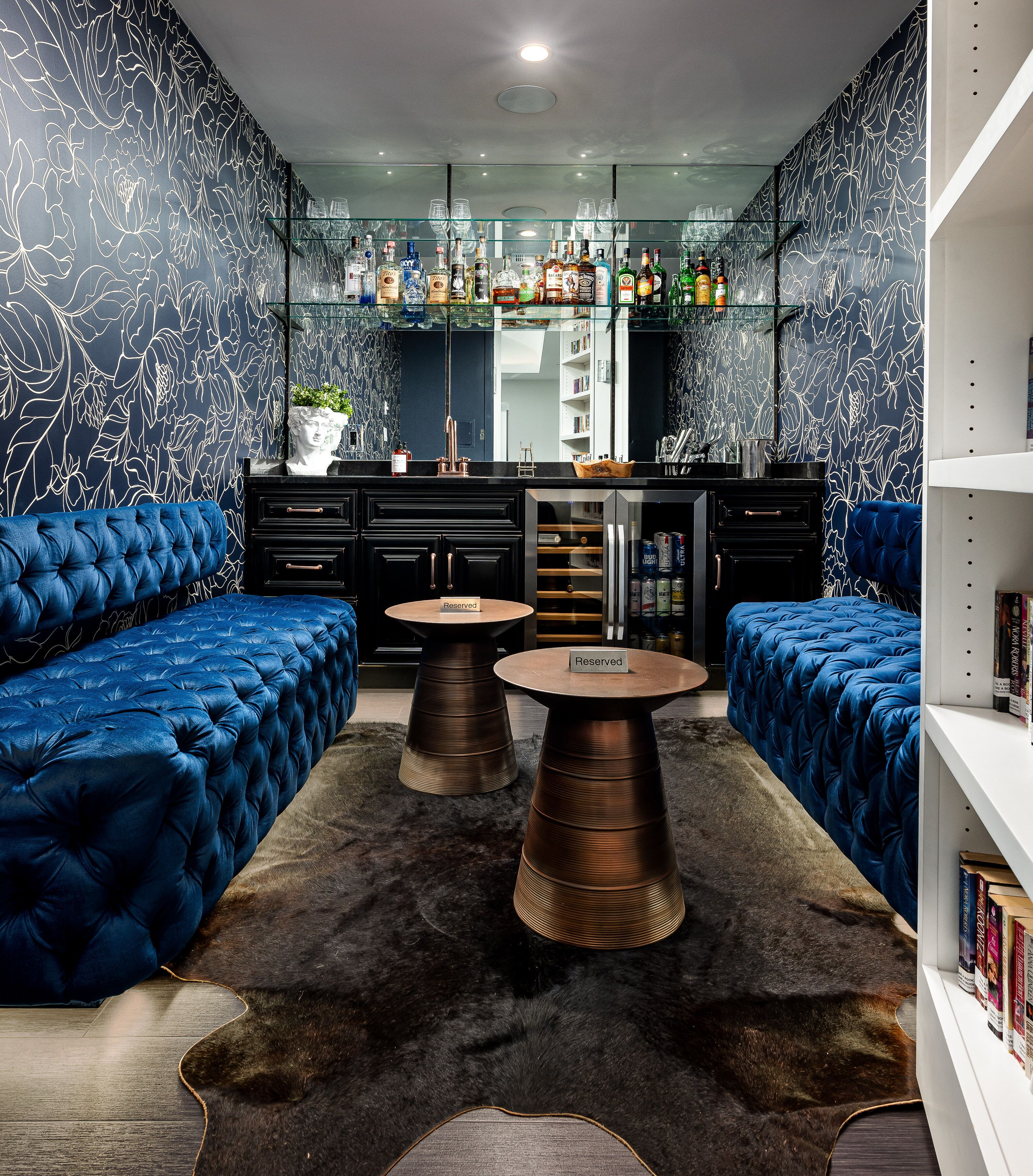 A modern living room with a sofa, two coffee tables, a fireplace, and a bookshelf.