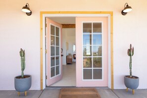 A hotel entrance with a double door, two potted cacti, and a doormat.