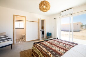 Een slaapkamer met een groot bed, een wasmachine en uitzicht op buiten.