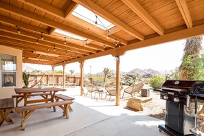 Eine Außenpatio mit Holzmöbeln, einem Grill und Blick auf die Wüstenlandschaft.