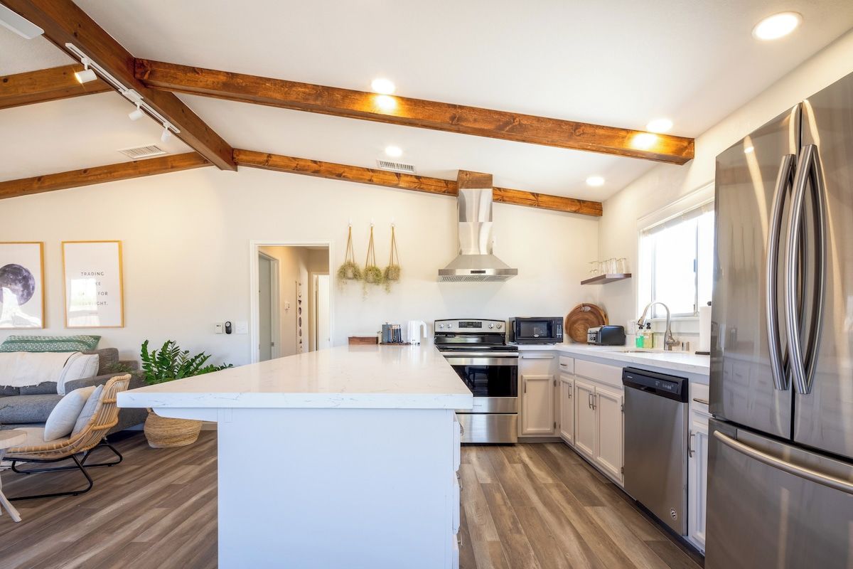 Una cocina moderna con una isla central, electrodomésticos de acero inoxidable y vigas de madera a la vista.