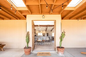 A wooden ceiling with skylights, a reception area with a welcome mat, and a view into a dining area.