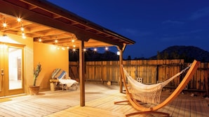 A wooden deck with a hammock, a chair, and a potted plant.