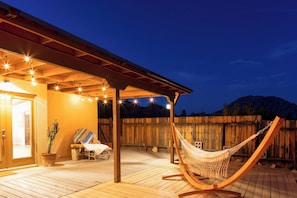 A wooden deck with a hammock, a chair, and a potted plant.
