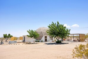 A desert landscape with a single building featuring a dome-shaped roof and a small porch area.
