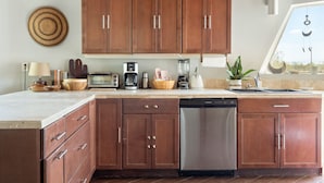 A modern kitchen with wooden cabinets, a dishwasher, a coffee maker, and a blender.