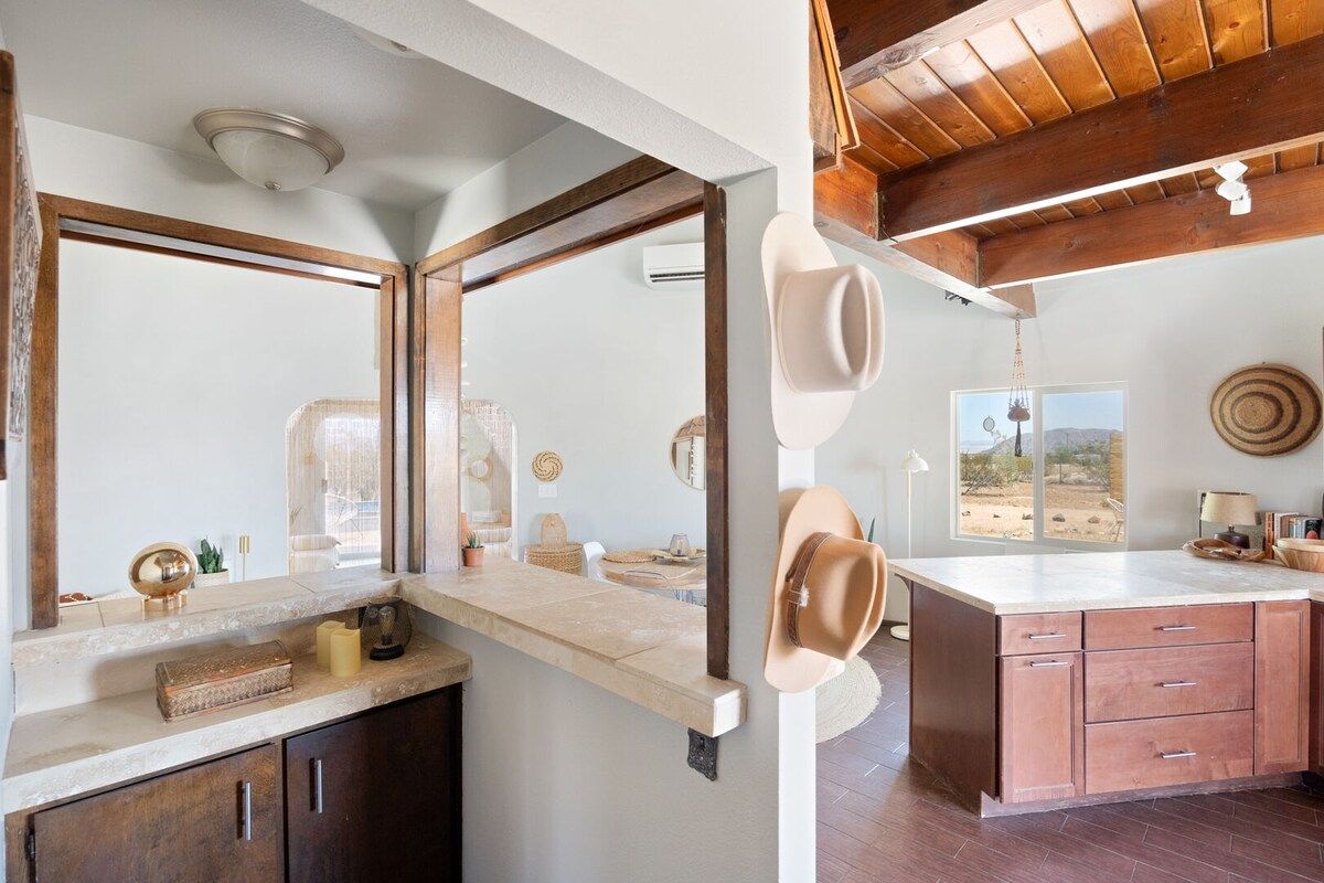 A kitchen with a large island, wooden cabinets, and a hanging hat.