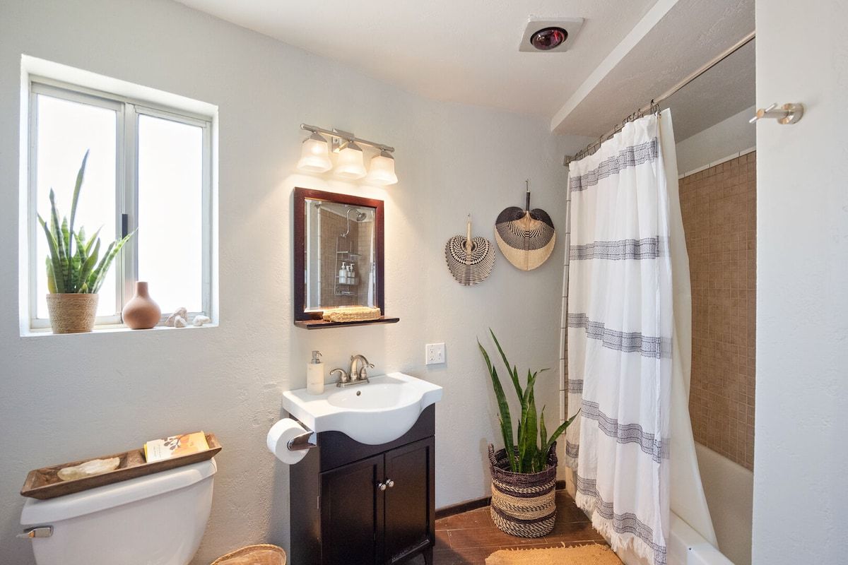 Ein Badezimmer mit Toilette, Waschbecken, Spiegel und Duschvorhang.