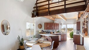 A spacious kitchen with wooden cabinets, a central island, and a dining area with a round table and chairs.