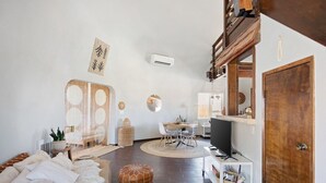 A modern living room with a sofa, ottomans, a dining area, and a television. - Abracadabra Dome in the Desert-Unique Experience! (Landers)