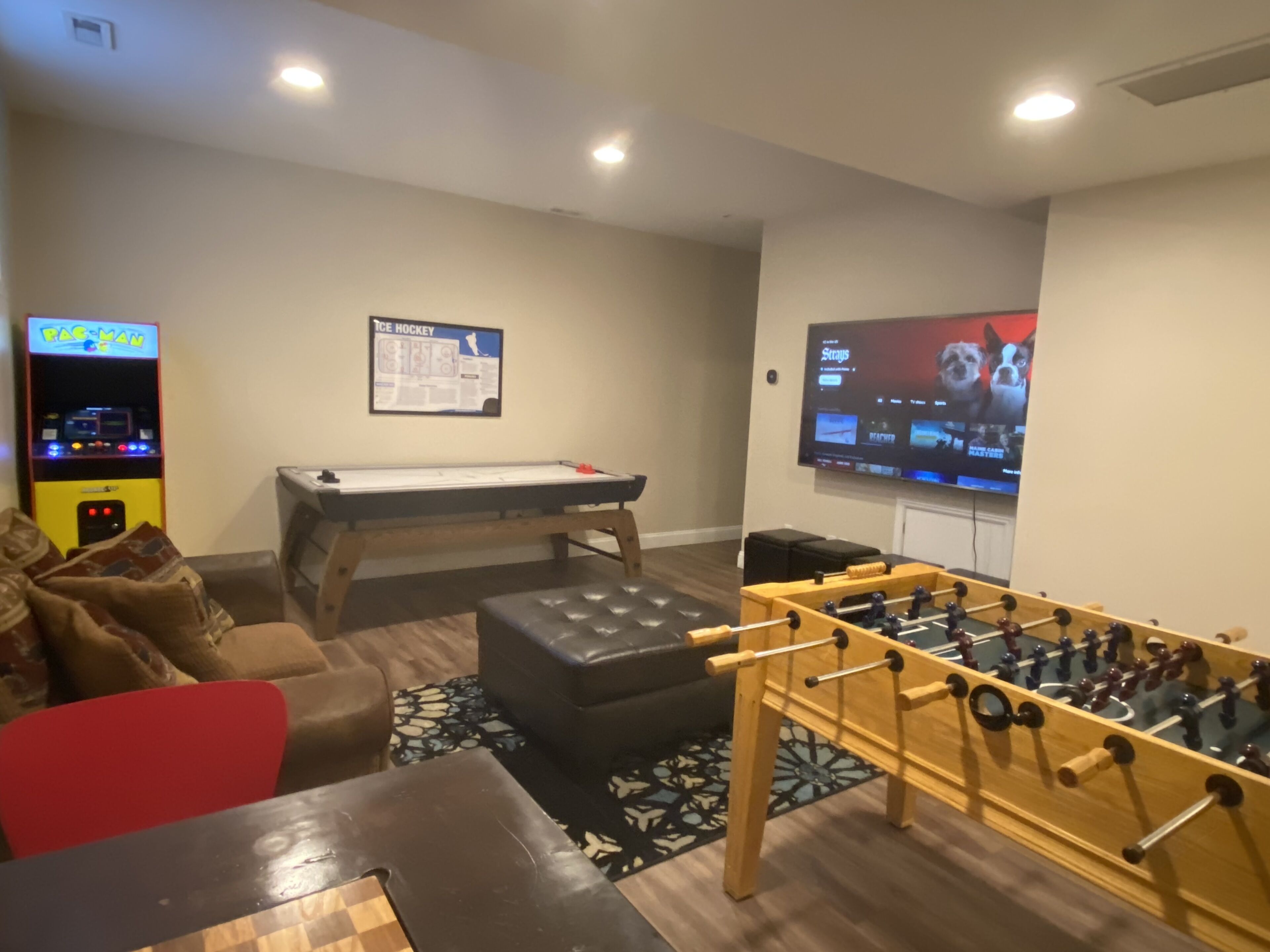 A recreational room with a foosball table, pool table, and a pinball machine.