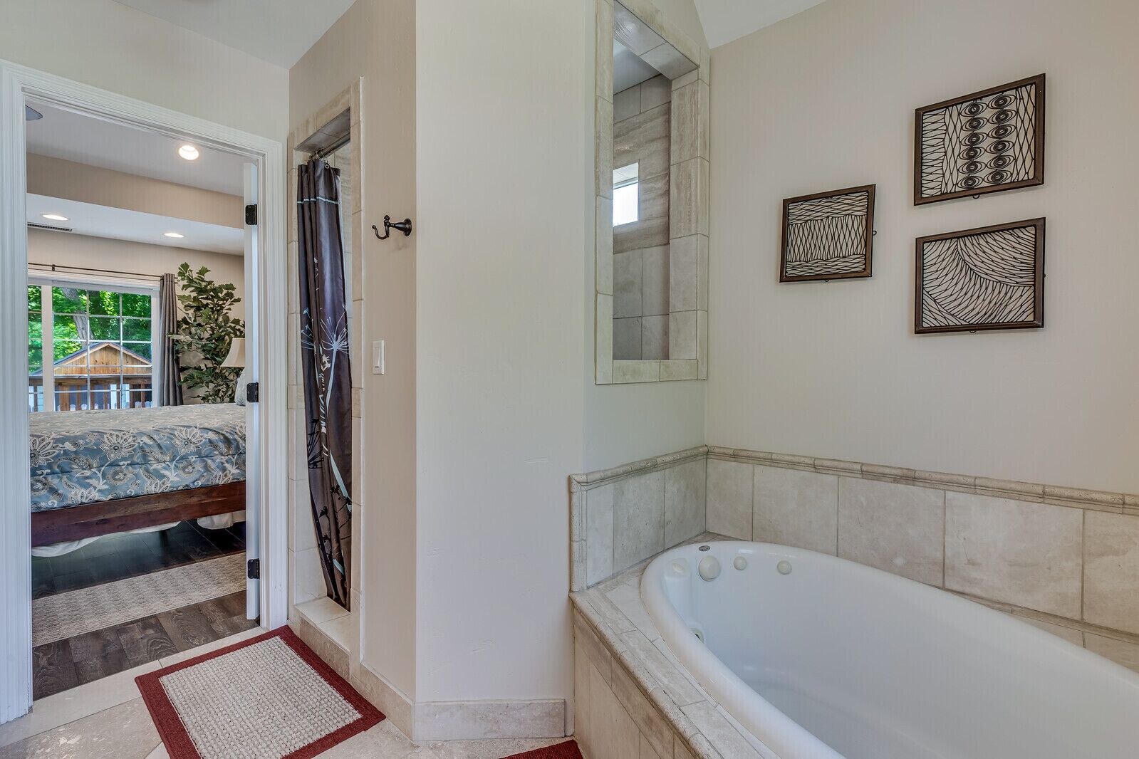 Ein Badezimmer mit einer Badewanne, einer Dusche und einer Tür zum Schlafzimmer.
