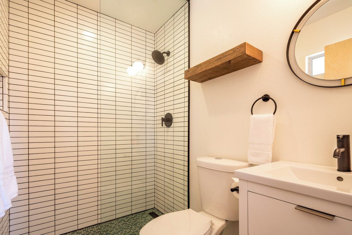 Ein Badezimmer mit Toilette, Waschbecken, Spiegel und Duschbereich.
