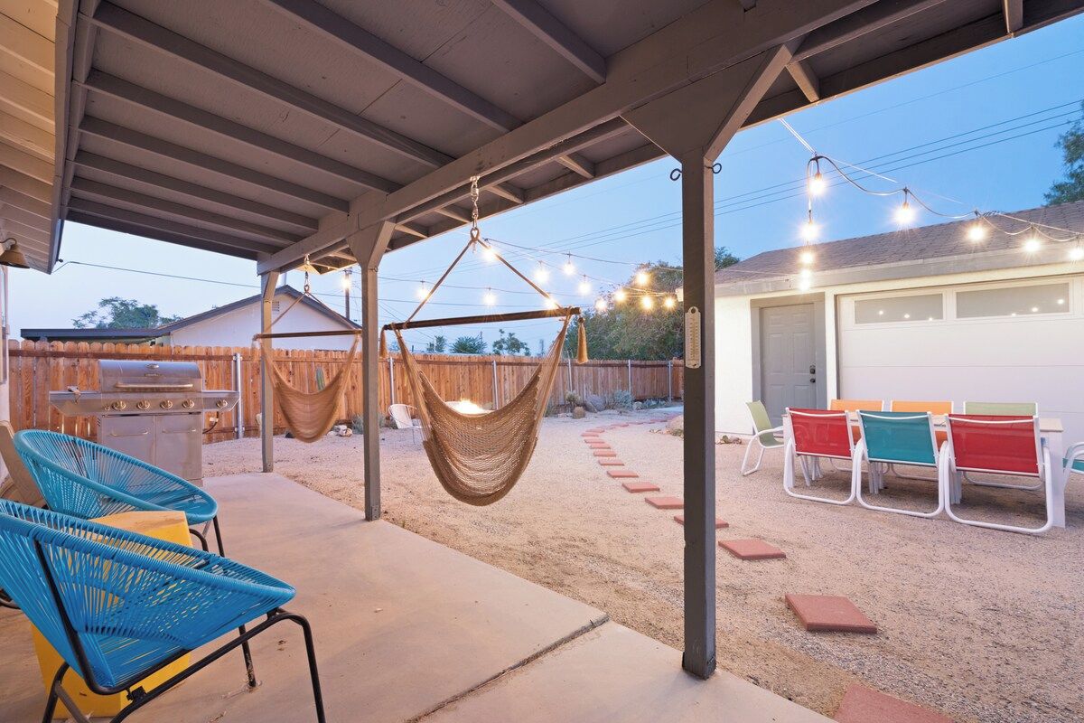 A covered outdoor patio with a grill, hammock, and outdoor seating area.