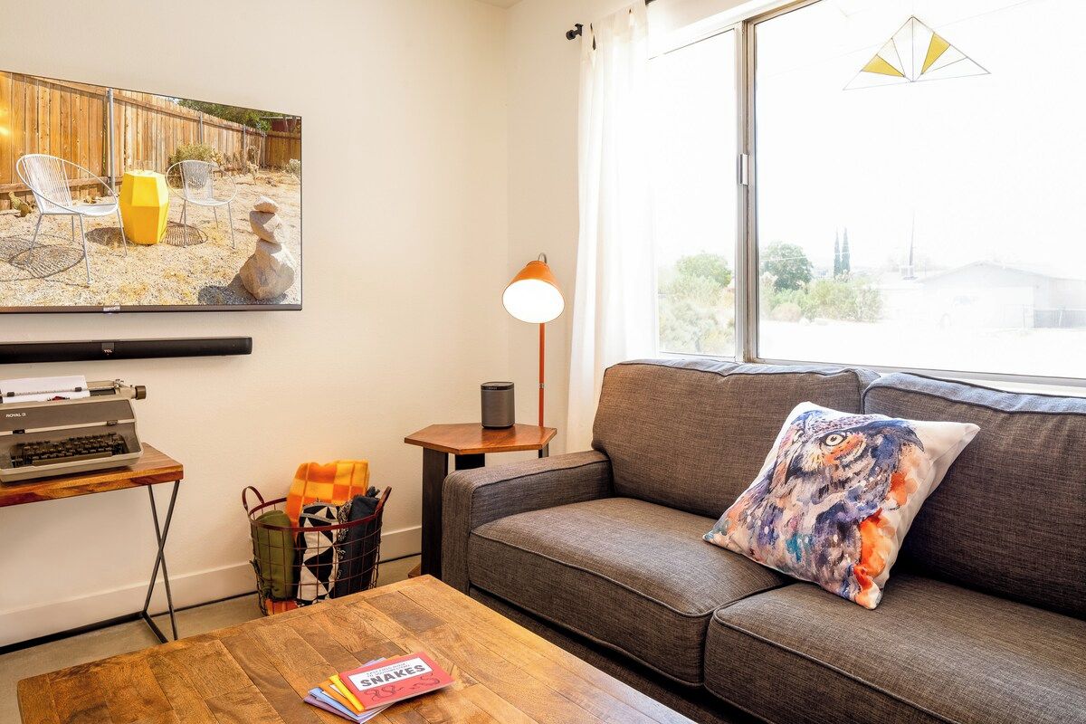 A living room with a sofa, a coffee table, a TV, a lamp, and a window with a view.