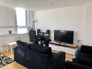 Relax in this stylish living room with a large flat-screen TV, comfortable sofa, and a desk area.