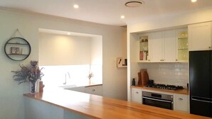 Una cocina moderna con armarios blancos, un refrigerador negro y una encimera de madera.