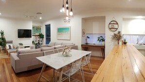 Una sala moderna con sofá, mesa de comedor y zona de cocina.