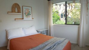 Un dormitorio con cama, ventana con cortinas y adornos en la pared.