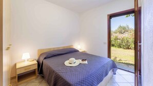 Un dormitorio con cama, lámparas de noche, mesita de noche, un sombrero y un libro.