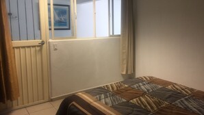 A bedroom with a bed, a window, and a door.