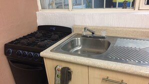 A kitchen with a stove, sink, and wooden cabinets.