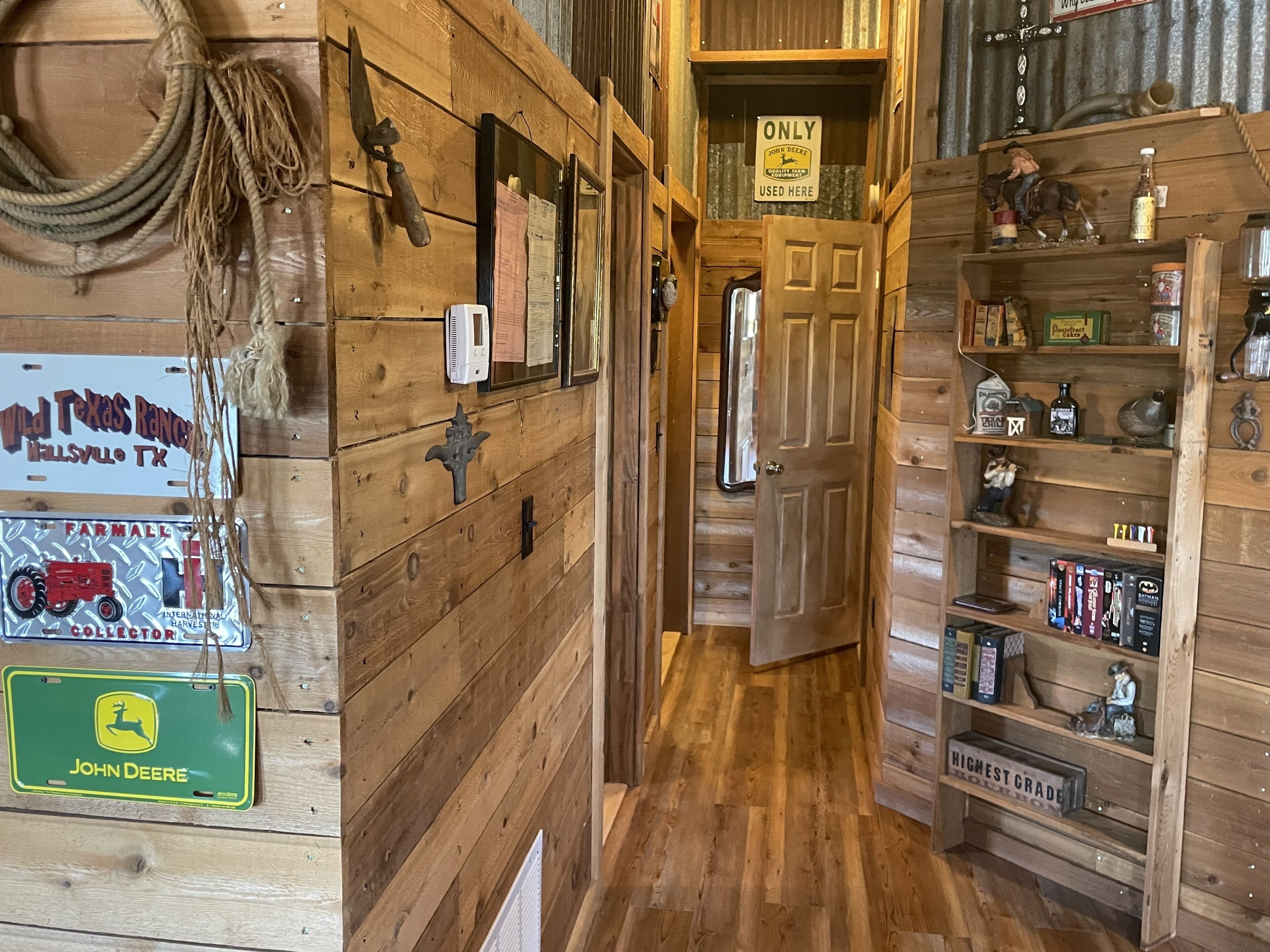 Un intérieur en bois avec un couloir étroit, une porte et des étagères remplies de divers objets.