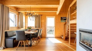 Ein Holzinnenraum mit Essbereich, Kamin und Blick ins Freie.