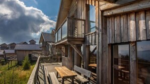 Eine Holzhütte mit einer Terrasse und großen Fenstern, umgeben von weiteren Hütten.