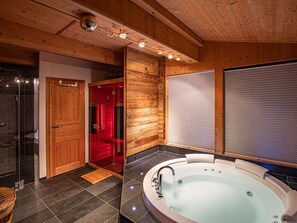 Ein modernes Badezimmer mit freistehender Badewanne, einer Duschkabine aus Glas und Holzvertäfelung.