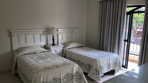 Et hotelværelse med to senge, et natbord, en lampe og udsigt ud