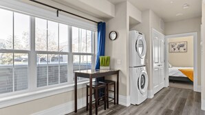 Une buanderie avec une grande fenêtre, une table avec des chaises et un lave-linge.