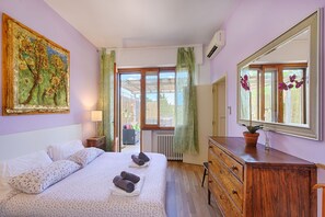 Quarto com cama, penteadeira, espelho, janela com cortinas e um quadro na parede.