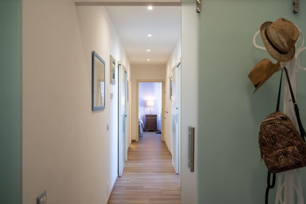 Un pasillo con piso de madera, cuadros en las paredes y una puerta que da a otra habitación.