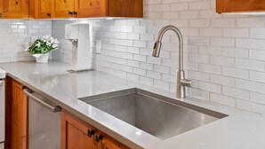 A kitchen with wooden cabinets, a stainless steel sink, and a white tiled backsplash. - Quiet tranquil setting. Updated townhouse Free parking, walk to Village and shops, common hot tub, (Whistler)