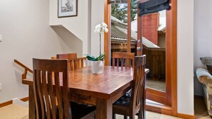 A wooden dining table with chairs, a potted orchid, and a framed picture on the wall. - Quiet tranquil setting. Updated townhouse Free parking, walk to Village and shops, common hot tub, (Whistler)
