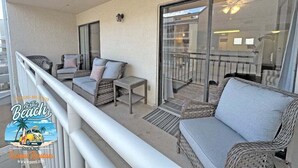Un balcon agrémenté de meubles en osier, une porte vitrée donnant sur le balcon et un ventilateur de plafond.