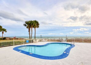 Relax by the oceanfront pool surrounded by palm trees and lounge chairs.