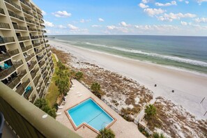 A high-rise hotel with a pool, beach view, and a pier extending into the ocean.