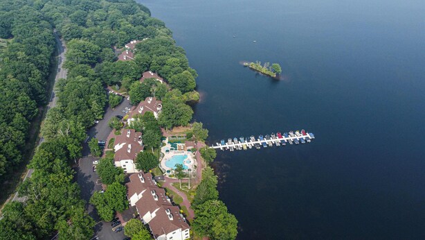 An aerial view of a lakeside property with a dock, swimming pool, and dense forest. - SLOPESVIEW 4,400sq ft ~ 3 Level Home~ 6 BR,4BA, Sleeps 16~ Games!Walk to slopes! (Lake Harmony)
