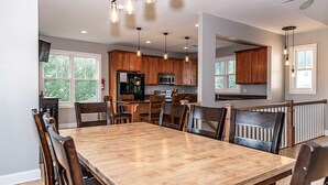 A spacious kitchen with wooden cabinets, a large dining table, and pendant lighting. - SLOPESVIEW 4,400sq ft ~ 3 Level Home~ 6 BR,4BA, Sleeps 16~ Games!Walk to slopes! (Lake Harmony)