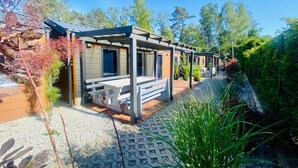 A row of cabins with wooden exteriors, each featuring a bench and a door. - Holiday Home in Dziwnów by the Baltic Sea (Dziwnow)