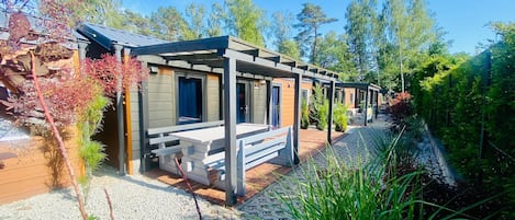 A row of cabins with wooden exteriors, each featuring a bench and a door.