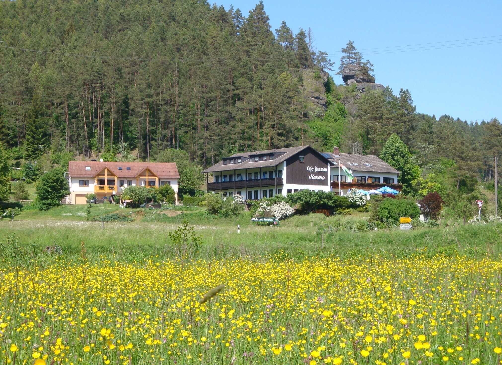 Ein Hotel mit großem Garten und einem Feld voller gelber Blumen im Vordergrund.