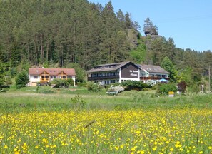 A hotel with a large garden and a field of yellow flowers in the foreground. - Café-Pension Krems - Double Room (Waischenfeld-Heroldsberg-Tal)