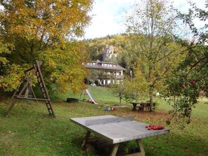 A house with a slide, a ping pong table, and a swing set in a grassy yard with trees. - Café-Pension Krems - Double Room (Waischenfeld-Heroldsberg-Tal)