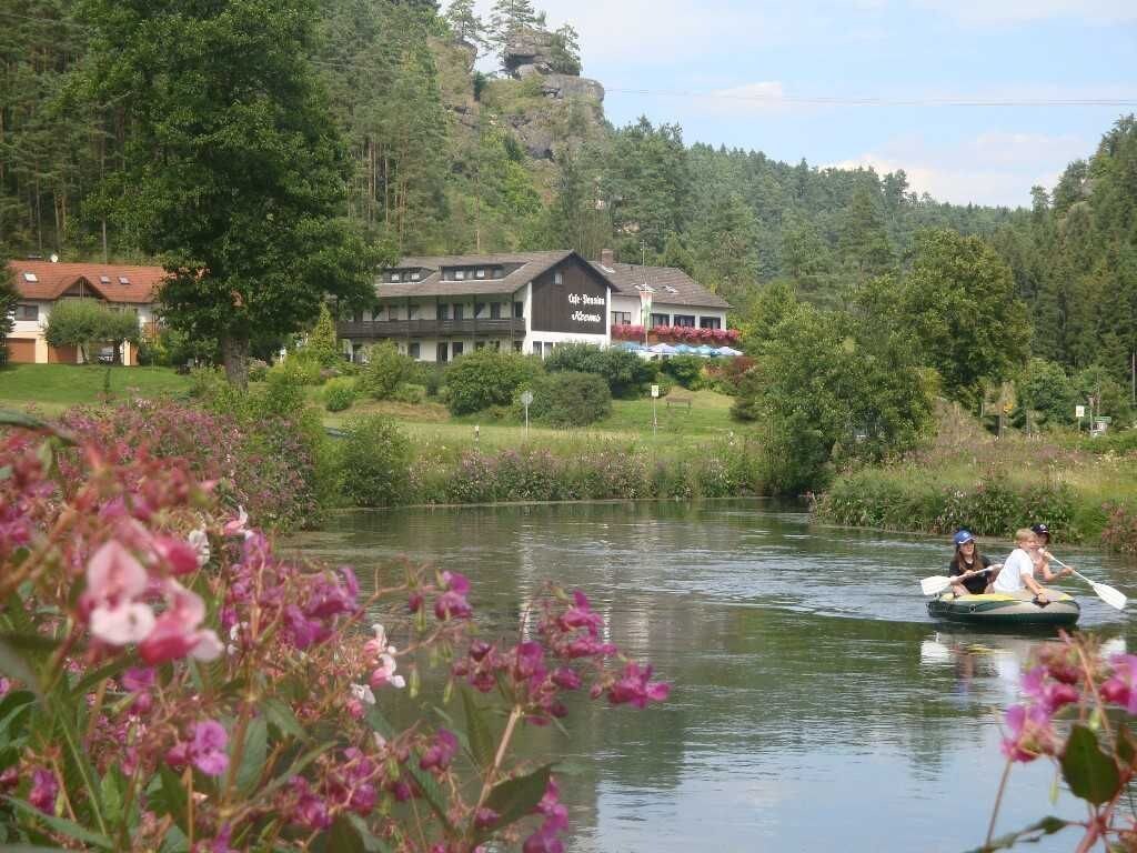 A lakeside hotel with a dining area, surrounded by greenery and a clear view of the lake.