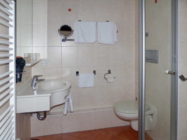 A bathroom with a sink, mirror, two towels, toilet, and a shower area.